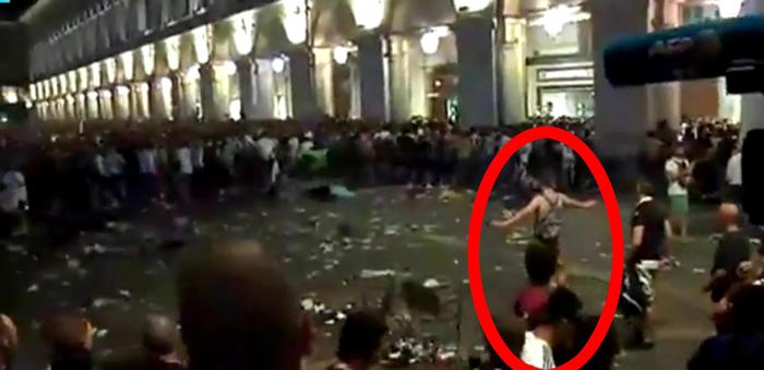 Un ragazzo a torso nudo, con lo zainetto sulle spalle, fermo nel caos di piazza San Carlo a braccia aperte: potrebbe essere lui ad aver scatenato il panico 